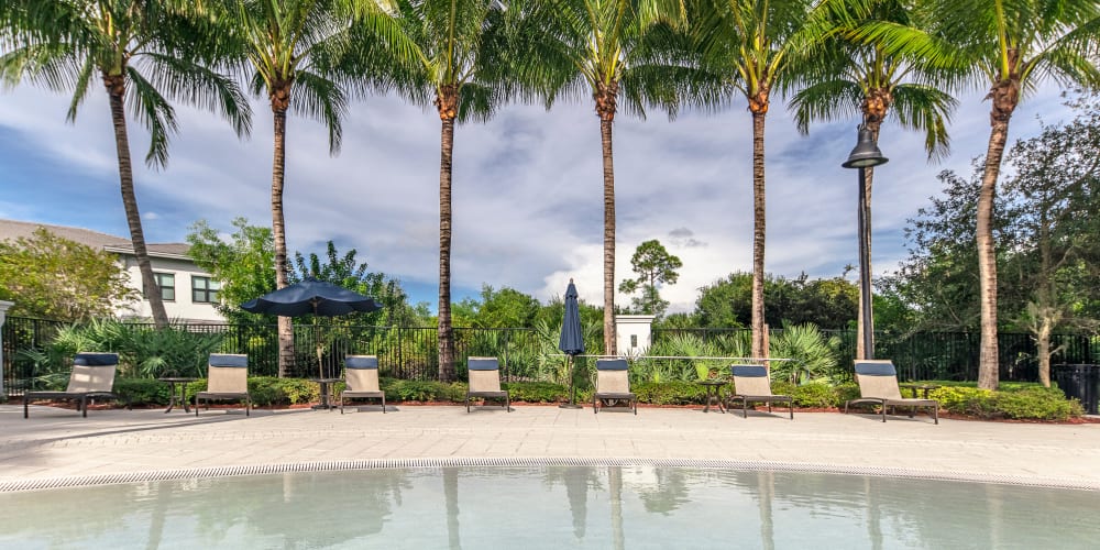 Seating by the pool at The Hamptons at Palm Beach Gardens Apartments in Palm Beach Gardens, Florida