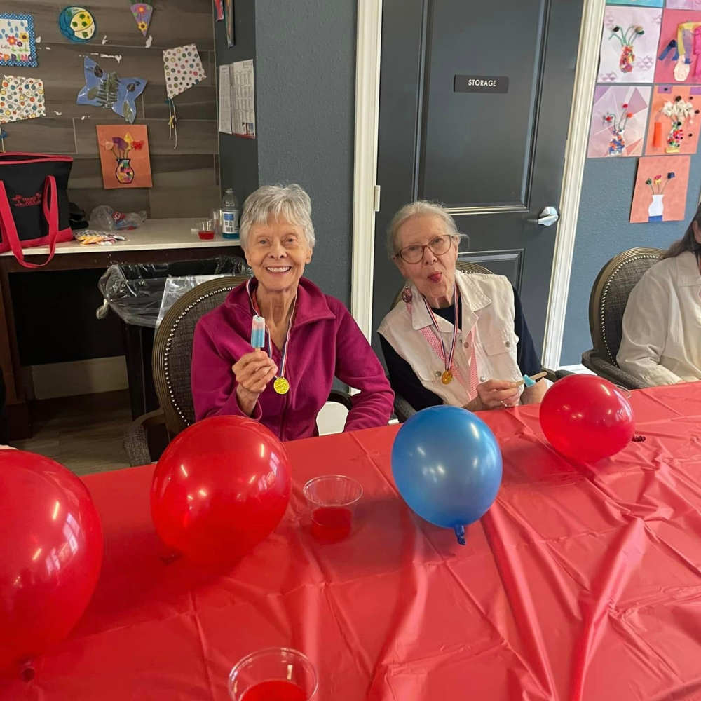 Memory care residents enjoying a colorful tabletop activity with balloons and crafts at Watermere Frisco.