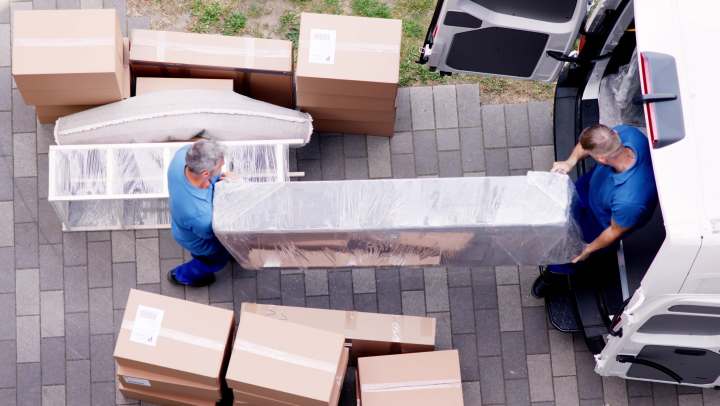 2 men loading boxes into a moving truck