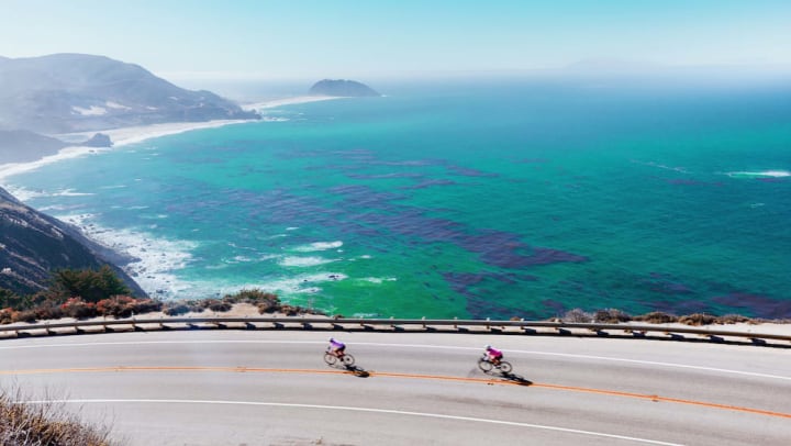 Cyclists riding down the Pacific Coast Highway with the ocean in the background