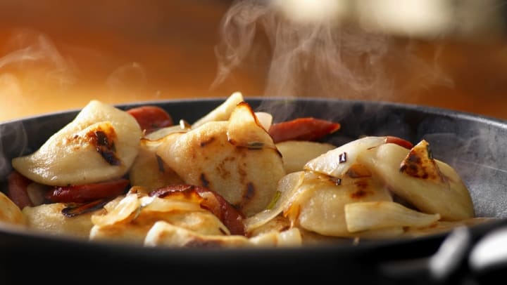 Close up of pan frying perogies with sausage and onions | piereogis in jacksonville