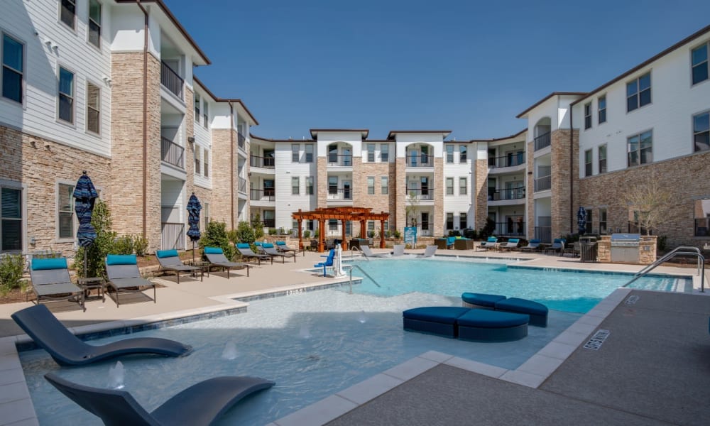 Large resort style swimming pool with lounges in the shallow end at Bellrock Upper North in Haltom City, Texas