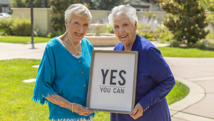 Two wonderful residents hold a "Yes You Can" sign!