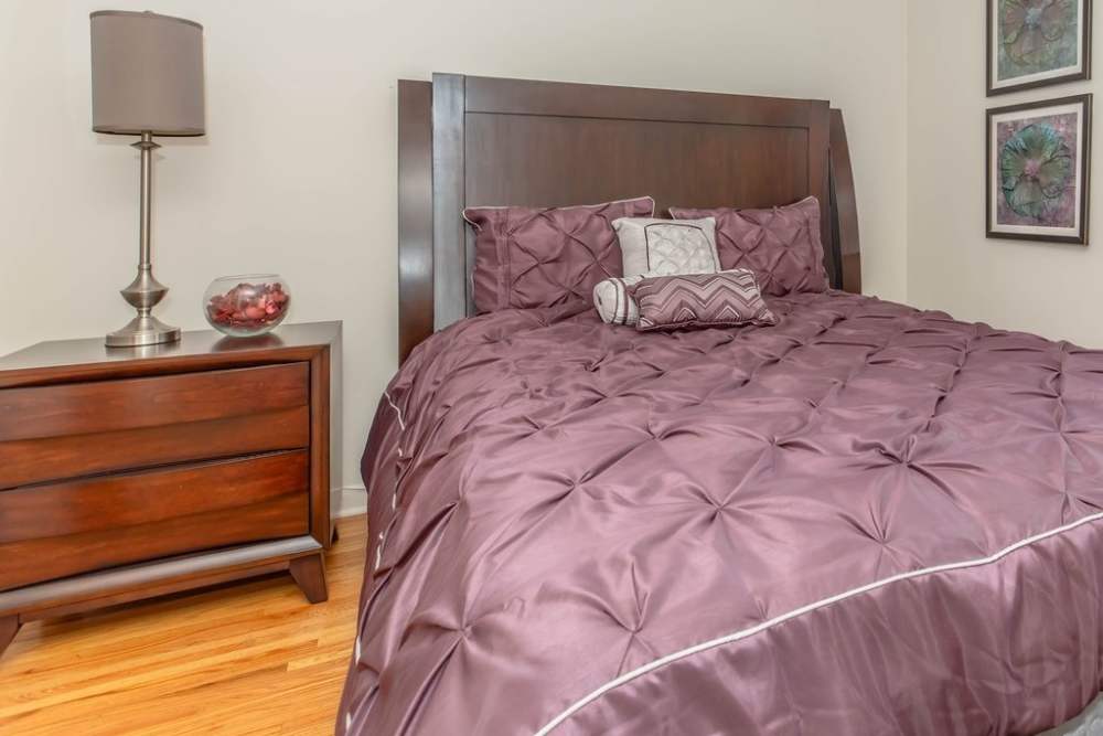Bedroom with a large comfortable bed at Greece Commons Apartments in Rochester, New York