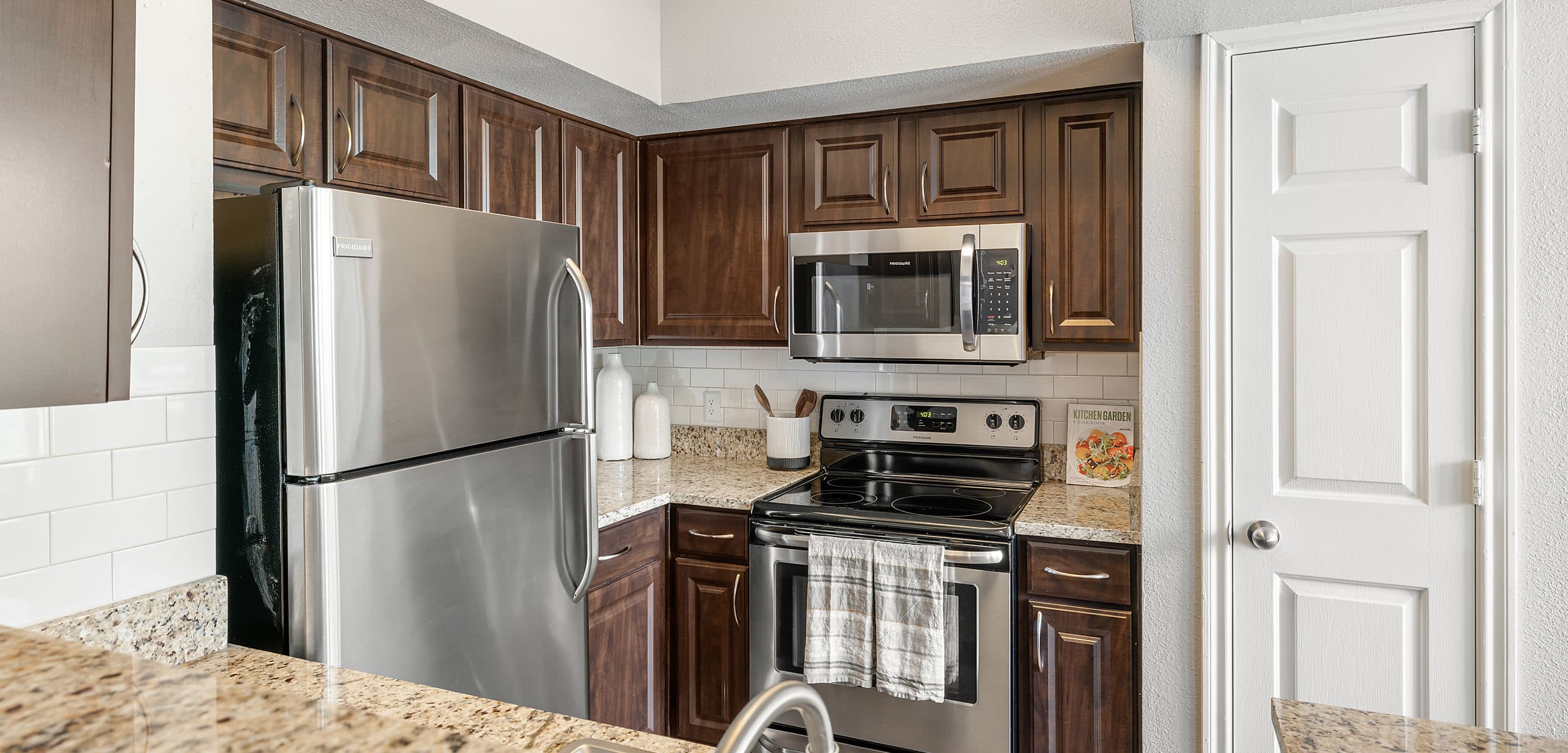 Modern kitchen with stainless steel appliances and granite counter tops at Marquis at Stonegate in Fort Worth, Texas