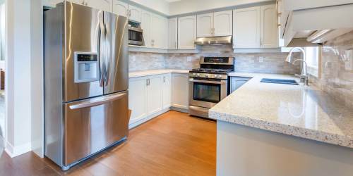 Modern kitchen with wood-style flooring and granite countertops at Comanche Hills in La Mesa, California