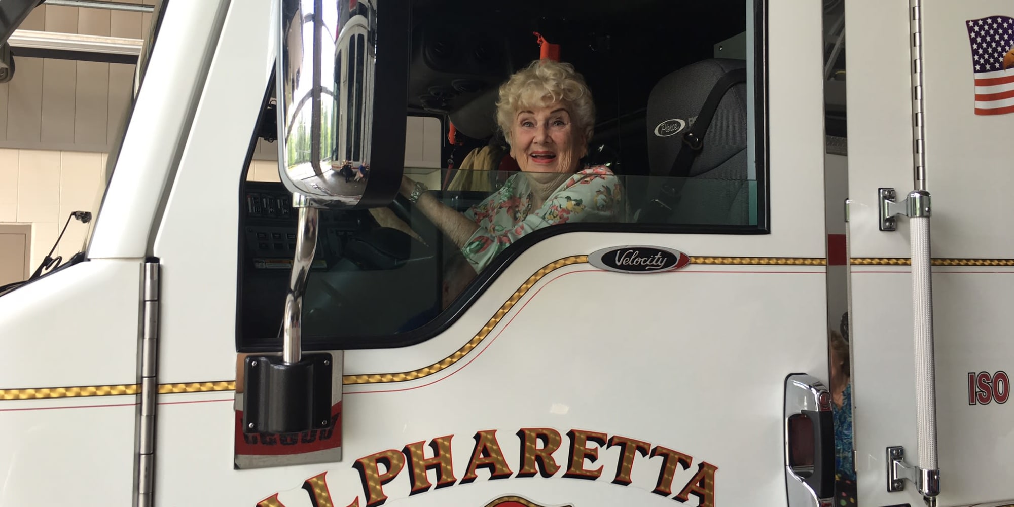 An excited resident from Cottonwood Estates Gracious Retirement Living in Alpharetta, Georgia in the driver's seat of a firetruck