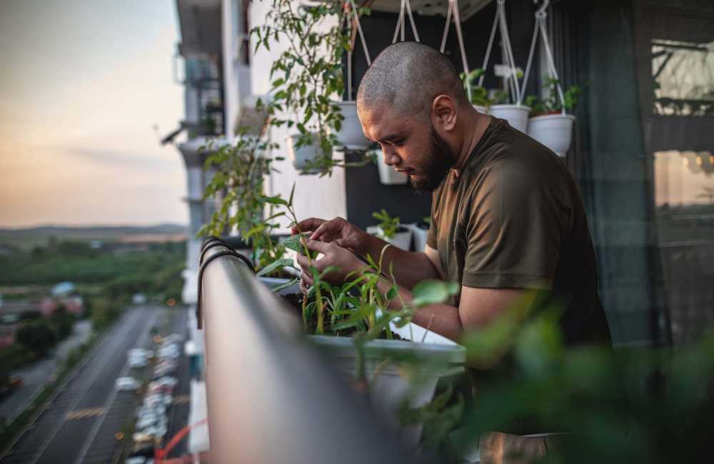 Resident tending to plants on his private balcony at Jefferson Cunningham Apartments in Los Angeles, California