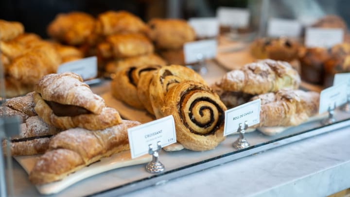 A bakery display featuring pastries like cinnamon rolls and croissants