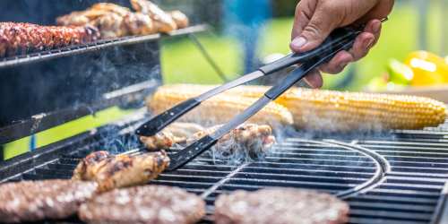 A person grilling meat and corn at an outdoor barbeque gathering at Clipper Cove in Tampa, Florida