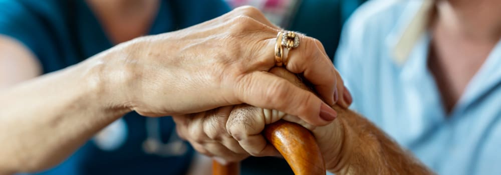 A staff member resting her hand on a Stoney Brook resident's hand 