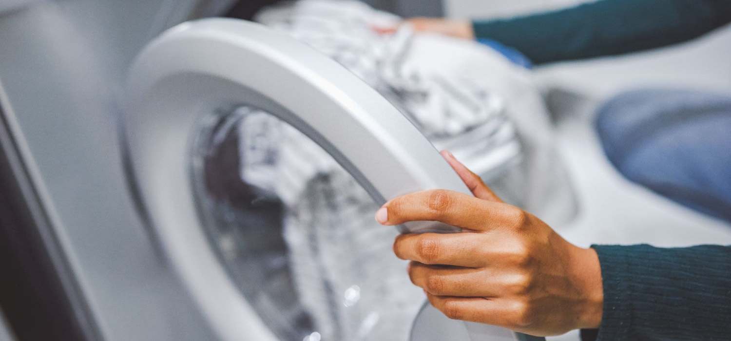 Woman putting clothes in washing machine at Cherrywood Apartments in West, Texas