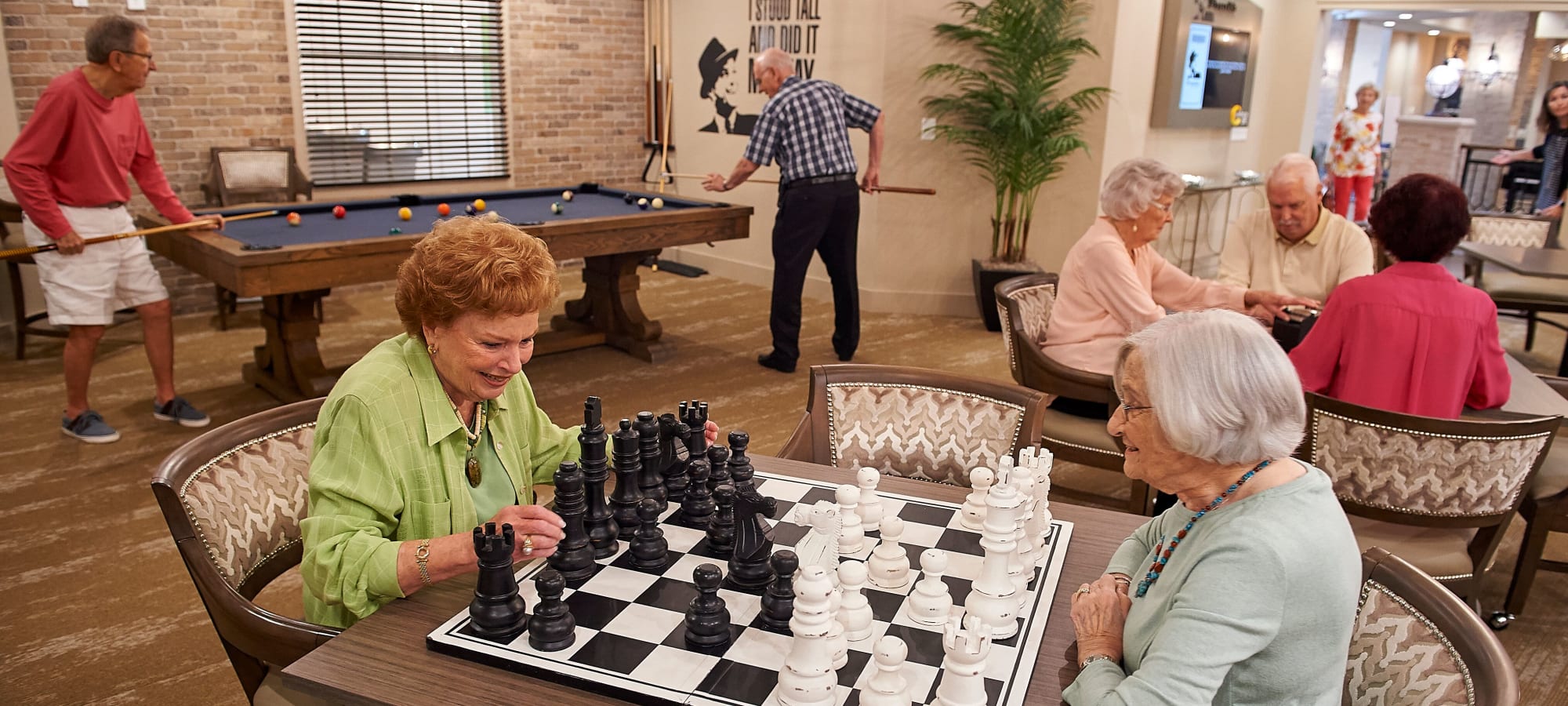 Residents playing chess in a game room at AgeWell Living