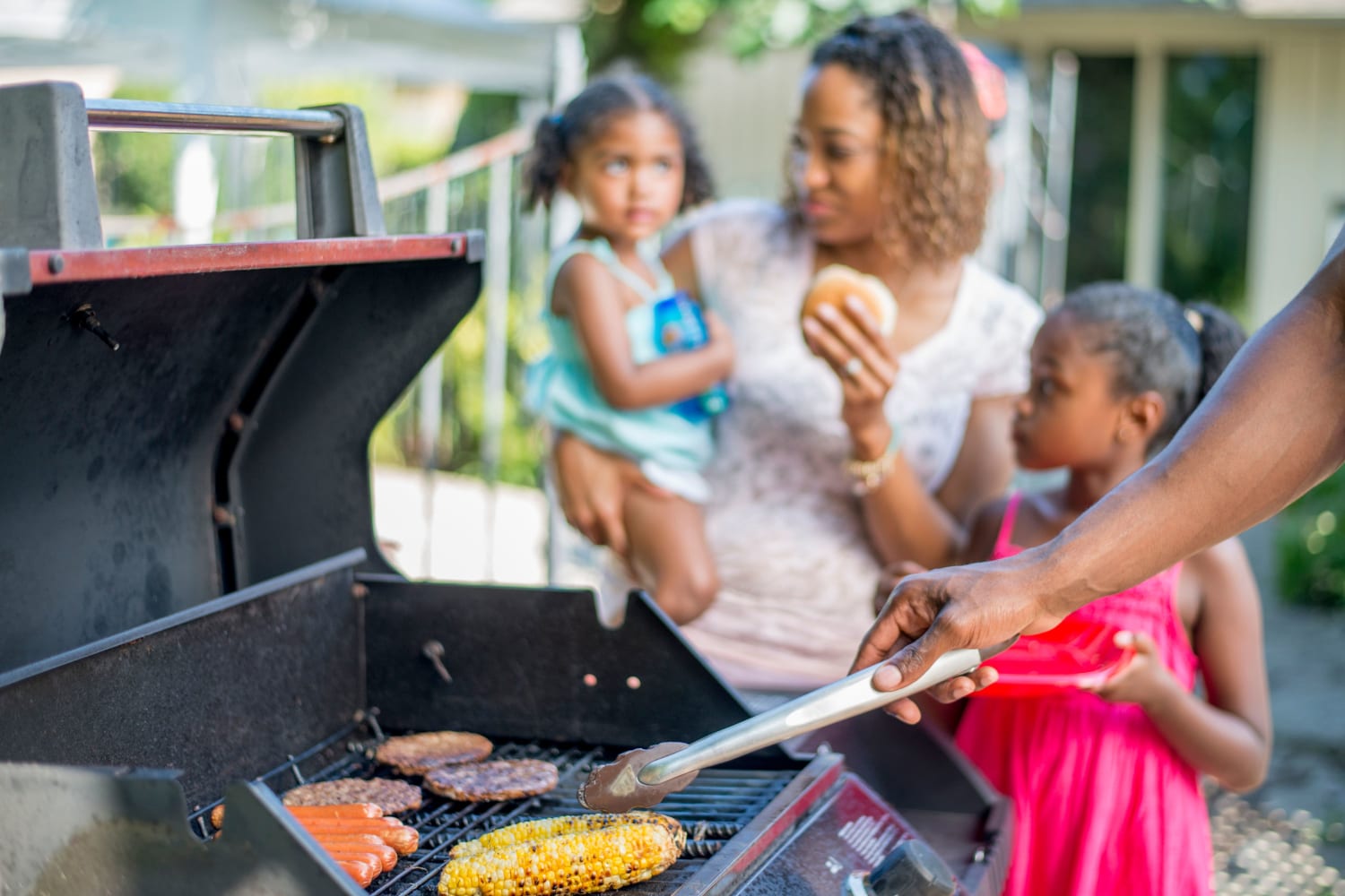 Family grilling at the bbq station near the pool at Parkway Apartments in Williamsburg, Virginia