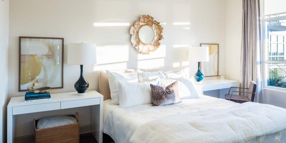 model unit bedroom furnished with bed, nightstand, mirror, curtains and white bedding at Park Central in Raleigh, North Carolina
