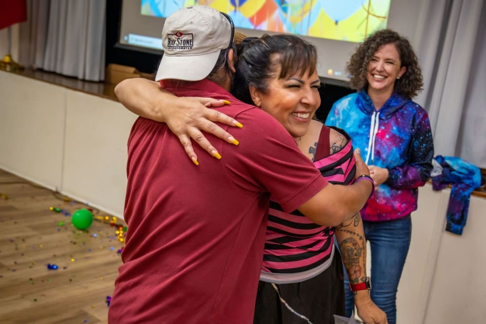 Individuals hugging at an event at Ray Stone Inc.