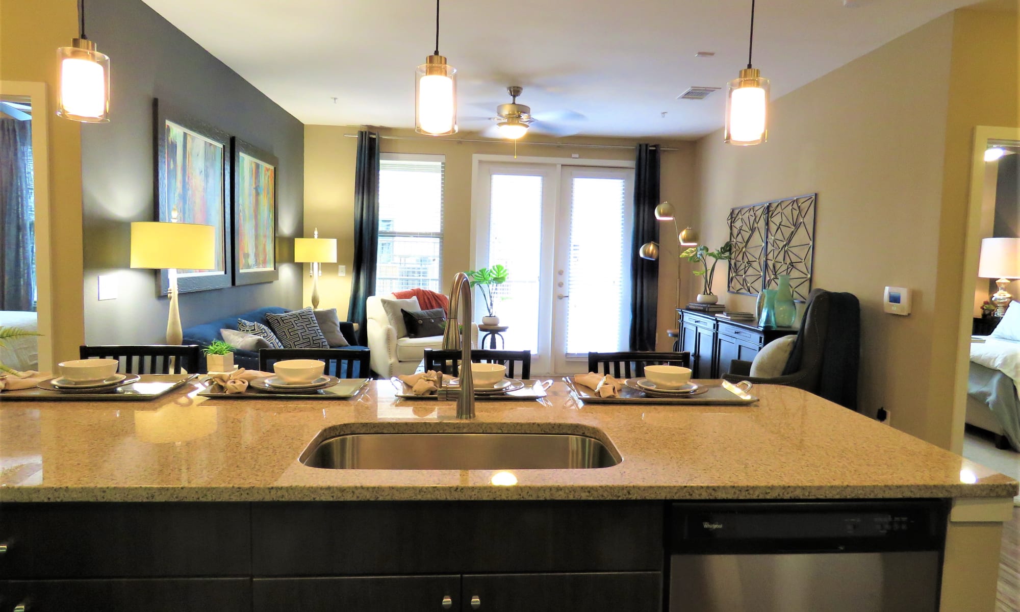 View of living room and kitchen from dining area in model apartment at The Abbey at Spring Town Center in Spring
