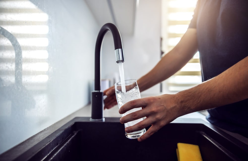 Resident filling a water glass from his apartment's gooseneck kitchen faucet at Las Terrazas in Colton, California