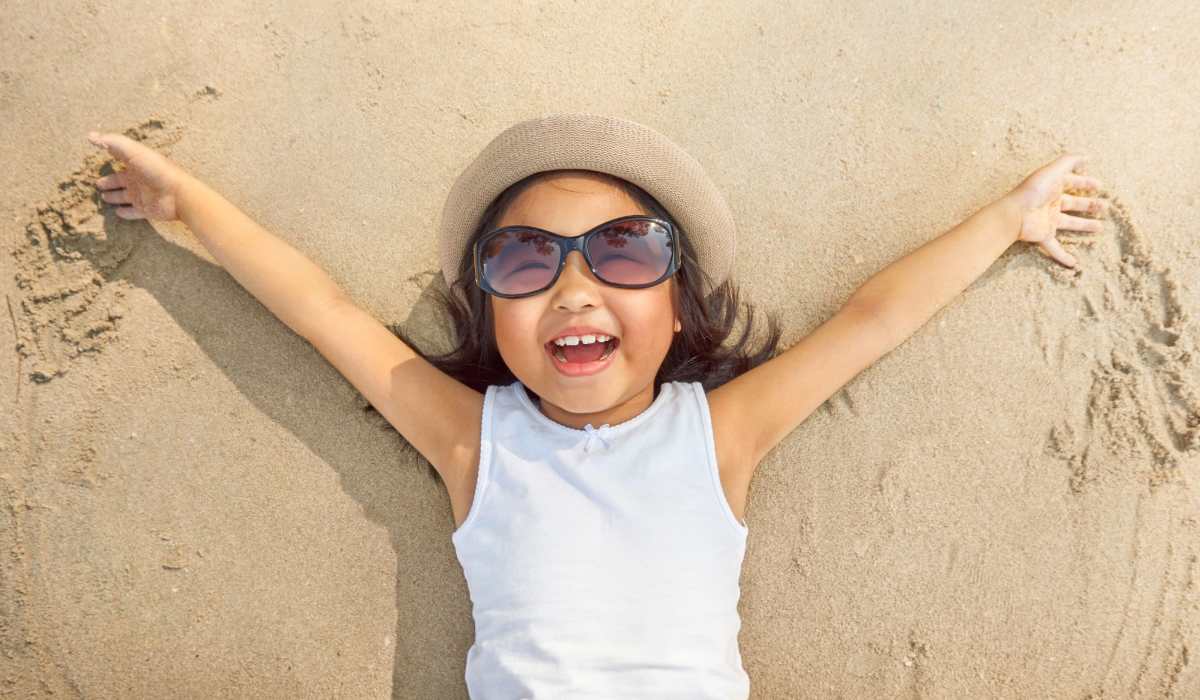 Smiling child laying on the sand at the beach near Seaton Preserve in Jacksonville, Florida