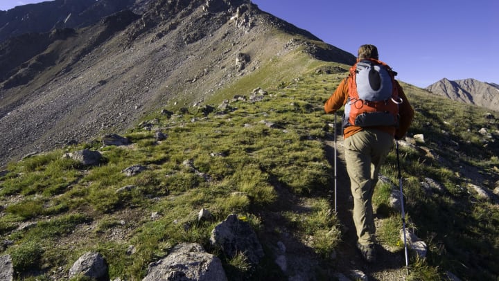 Man backpacks on a mountainous trail