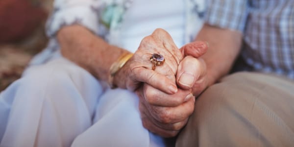 Seated resident couple holding hands at Transitions At Home - Central in Stevens Point, Wisconsin