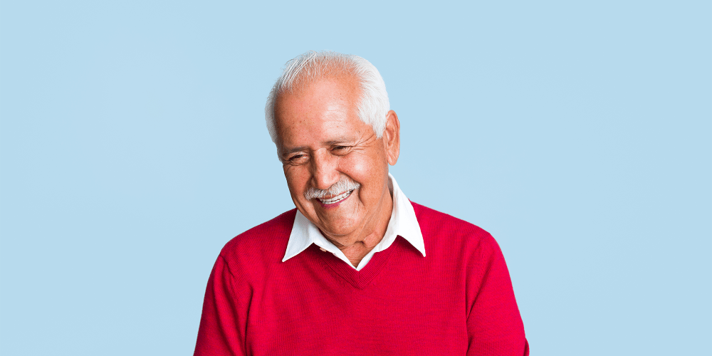 A smiling resident dressed in a white collar shirt and red sweater