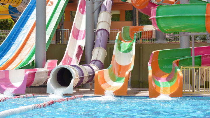 A variety of colorful water slides feeding into a pool of water.
