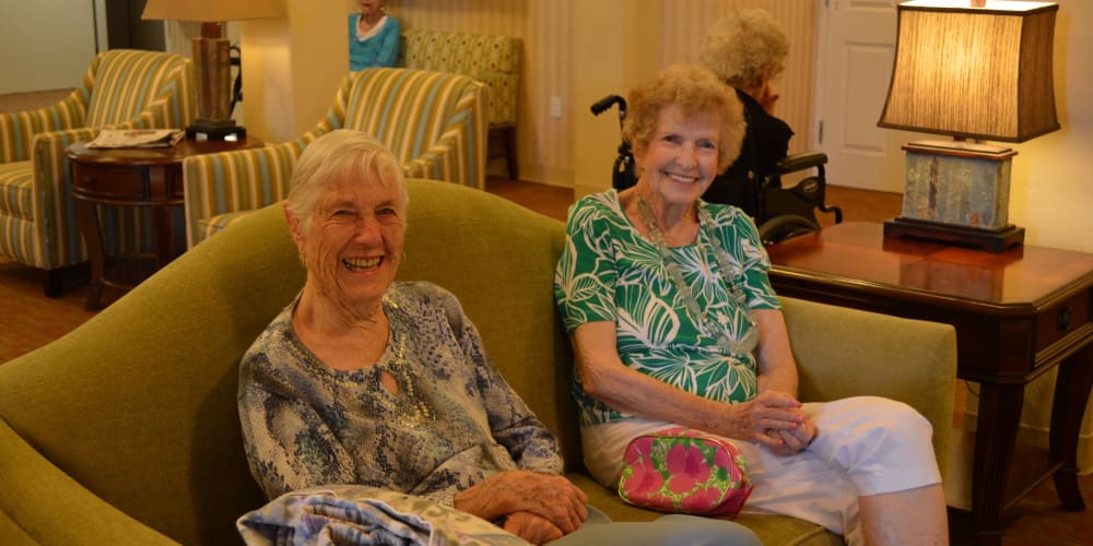 Two resident friends sitting on a couch at The Lakes at Banning in Banning, California. 