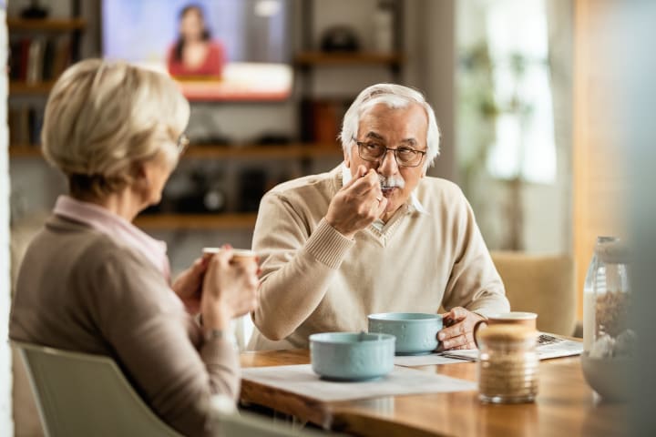 Senior man eating soup with wife