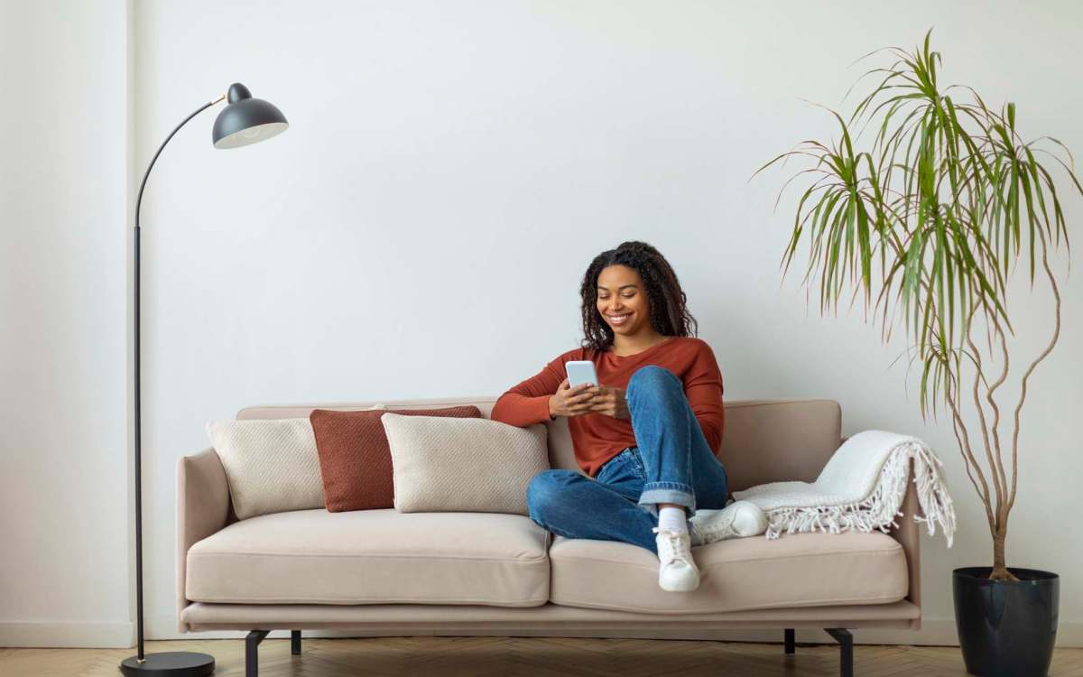 Resident using mobile while sitting in sofa at Aventura Residences at The Imperial Club in Aventura, Florida