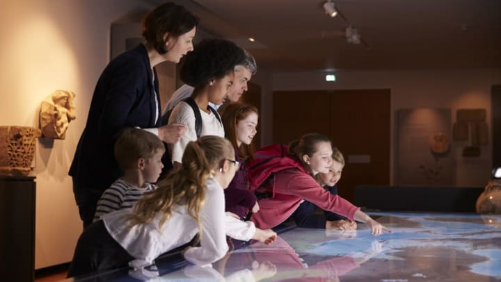 Female museum volunteer giving educational tours to children | museum volunteer around Carrollton