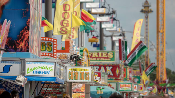 A fair midway filled with carnival rides and food stands.