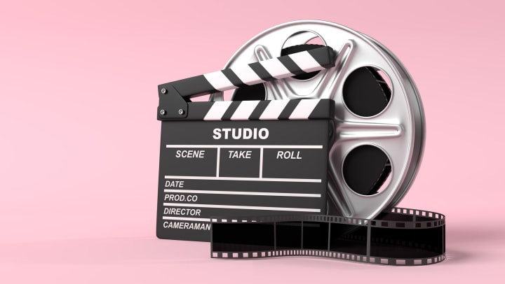 Movie film reel with a clapperboard on a pink background