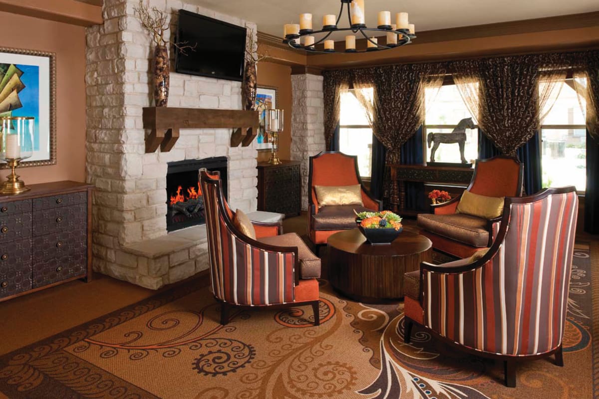 Cozy common area at Isle at Cedar Ridge in Cedar Park, Texas, with a fireplace and comfortable chairs.
