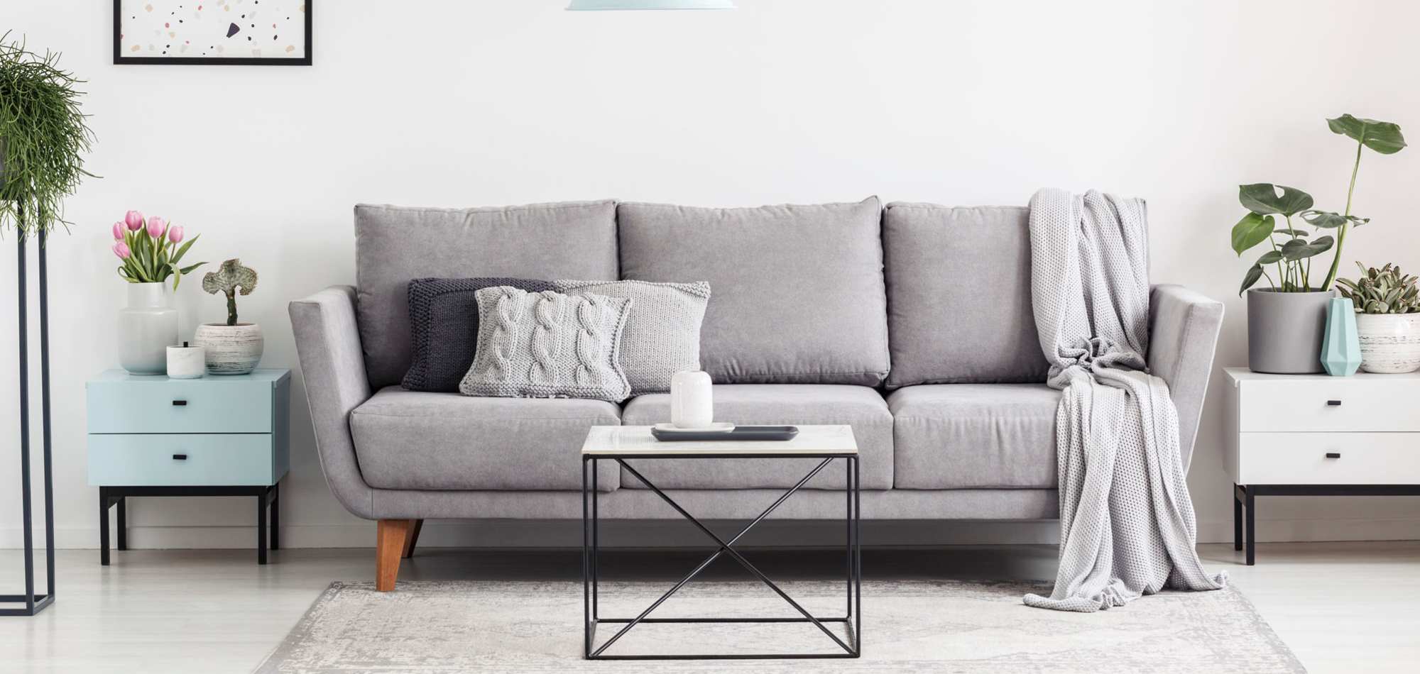 Gray sofa with decorative pillows and blanket at Avia Lofts at Maple Road in Amherst, New York
