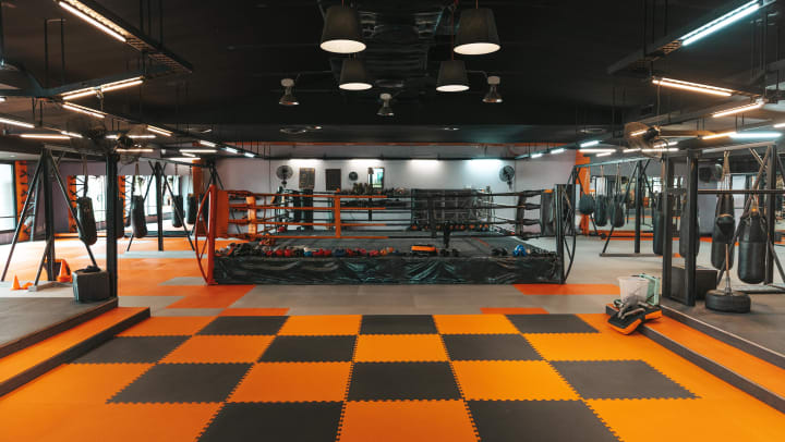 An empty kickboxing gym with various gym equipment such as punching bags and a boxing ring | MMA studios near Carrollton