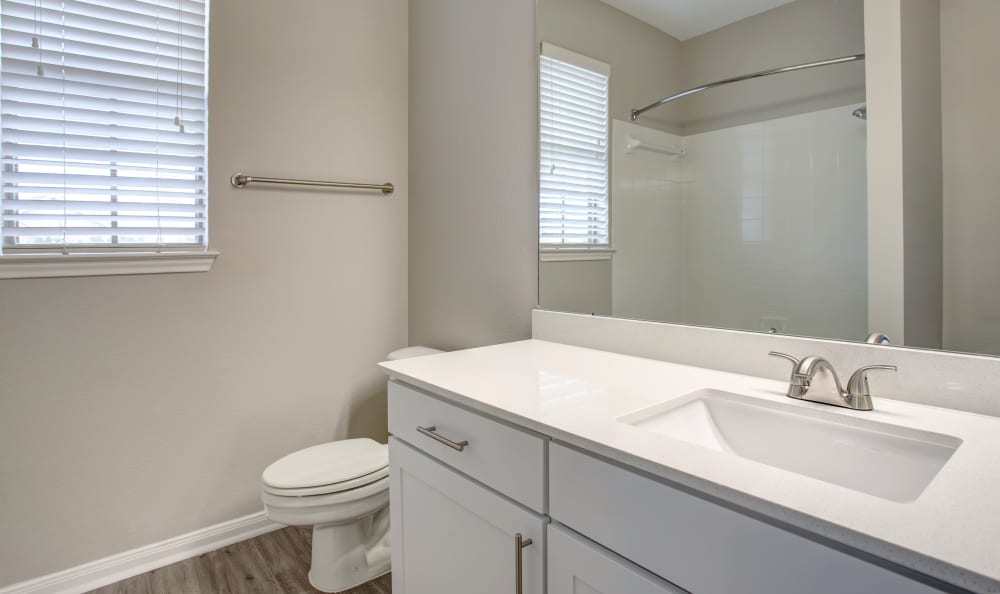 Quartz countertop and a large vanity mirror in a model home's bathroom at Riata Austin in Austin, Texas