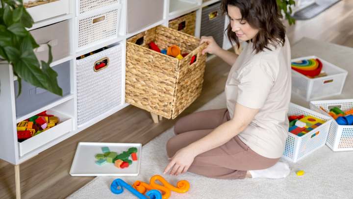 Woman organizing toys using decorative boxes