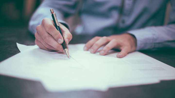 Picture of hands signing papers with a pen