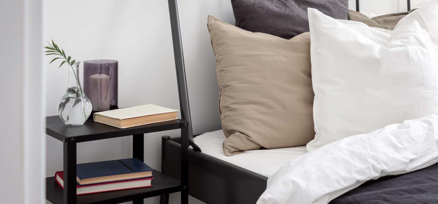 Spacious bedroom with a bed and a nightstand consisting of books and a candle at Indian Terrace Villas in Auburn, Indiana