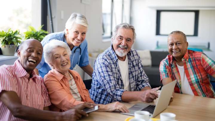 Elderly individuals around a table smiling and chatting.