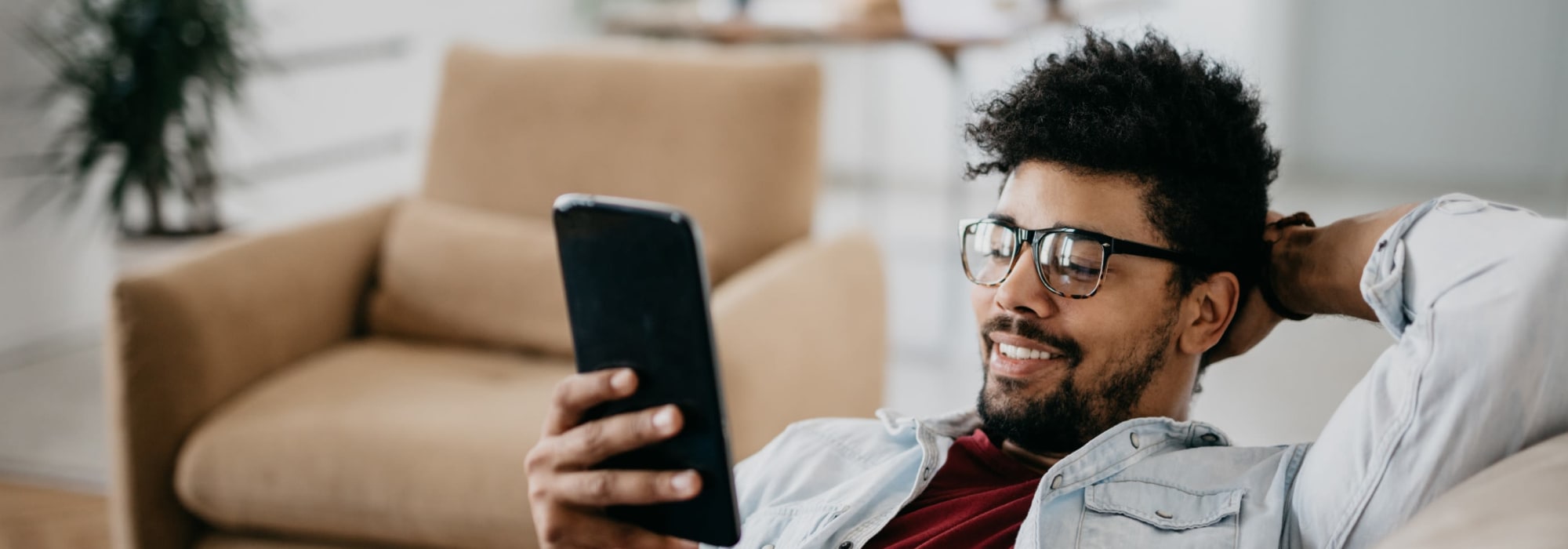 Man Reclining on a Couch and Looking at his Phone at 1221 Vallejo Apartments in Novato, California