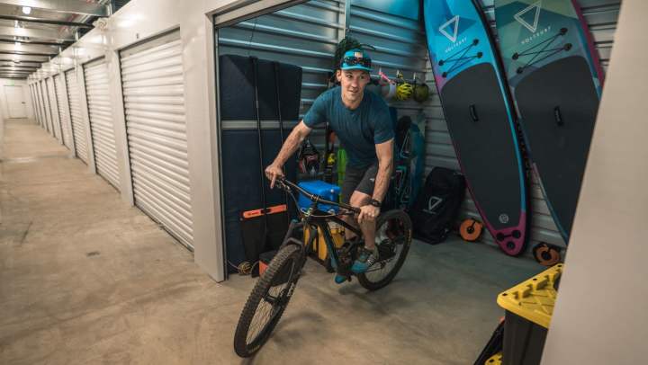 StorQuest client riding mountain bike out of storage unit