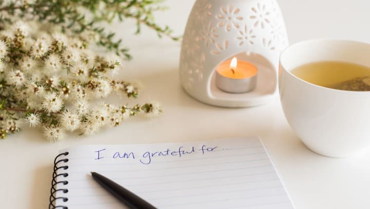 Notebook that says, “I am grateful for…” written at the top with a pen resting on the paper. 