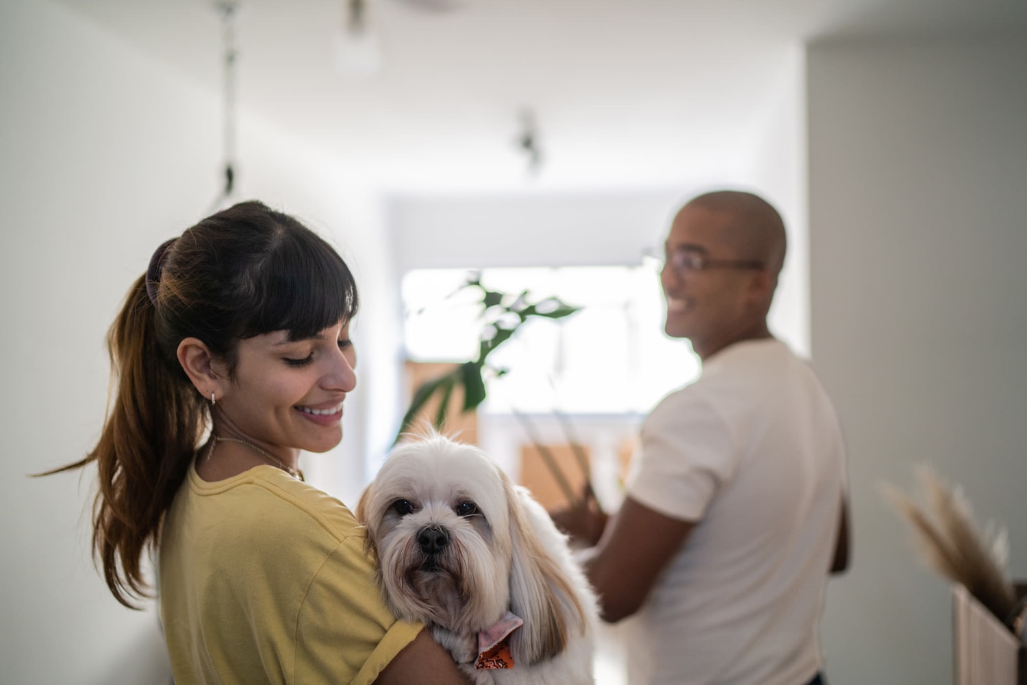 Happy dog being carried by a woman walking into her home with her partner  at Chapel Creek in Doraville, Georgia