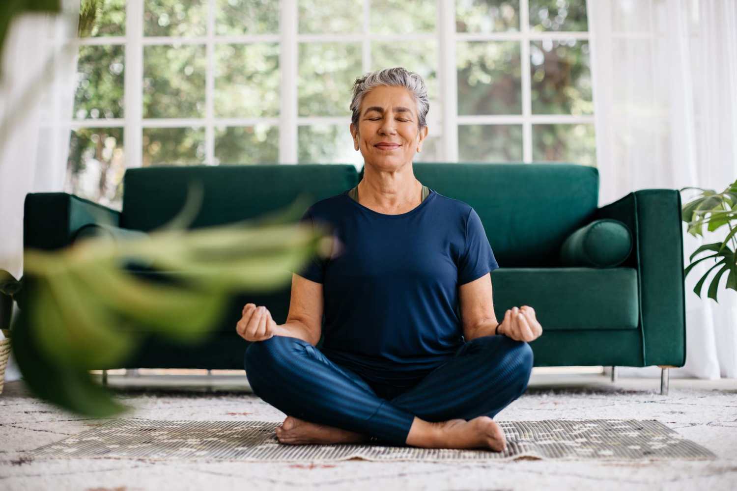 Senior woman practicing yoga in the living room of her apartment at Bramblewood in New Haven, Michigan