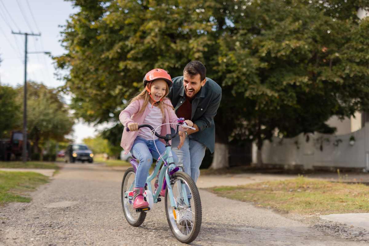 Father encouraging daughter riding bike near Homes at Fountain Green in Bel Air, Maryland 