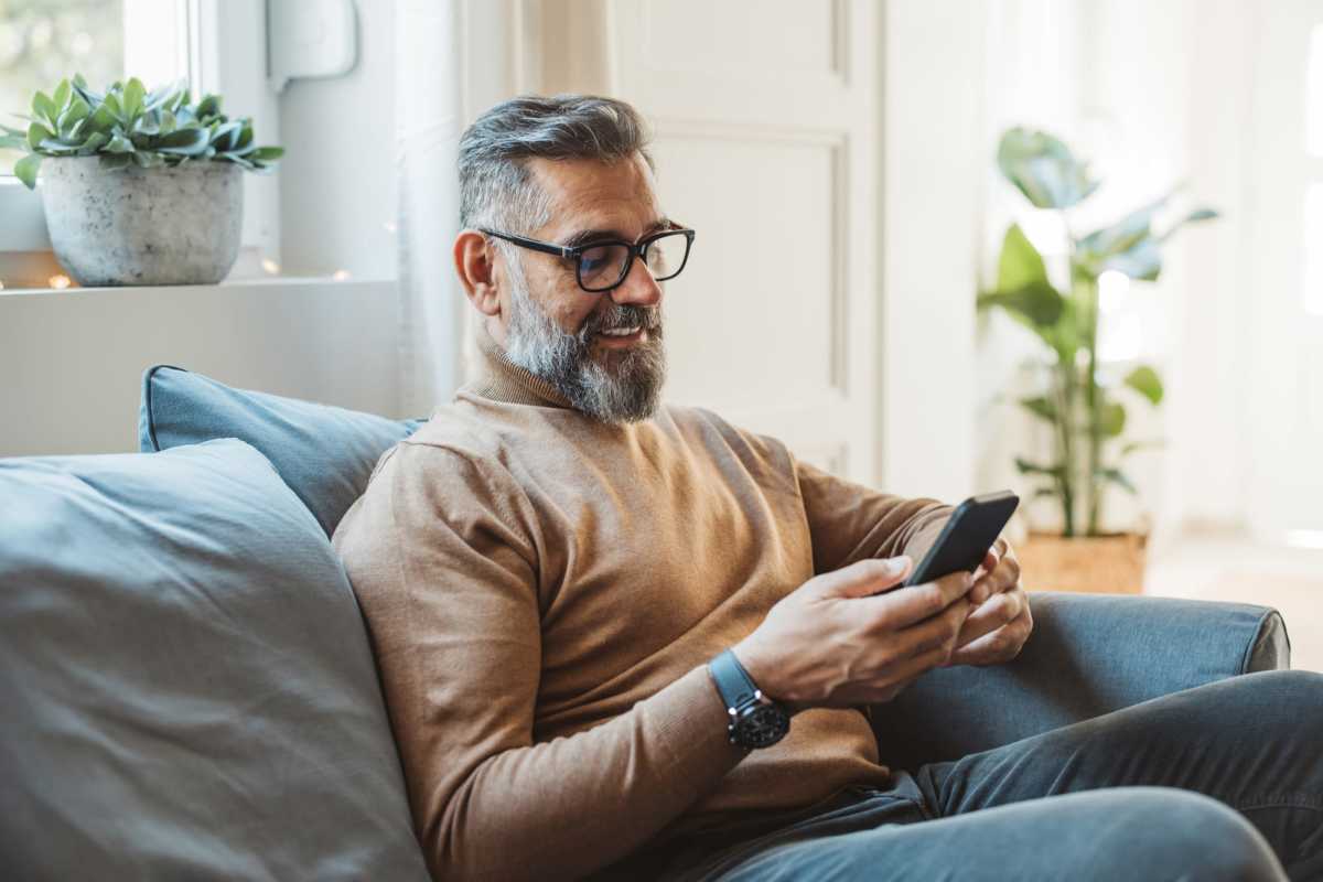 Man using smartphone while relaxing on sofa at Lincoln on the Park in Emmitsburg, Maryland 