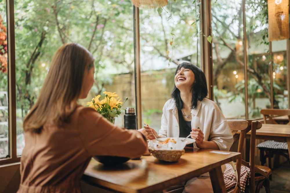 Residents seated at a wooden table in a bright café near Newport Sound Apartments in New Smyrna Beach, Florida