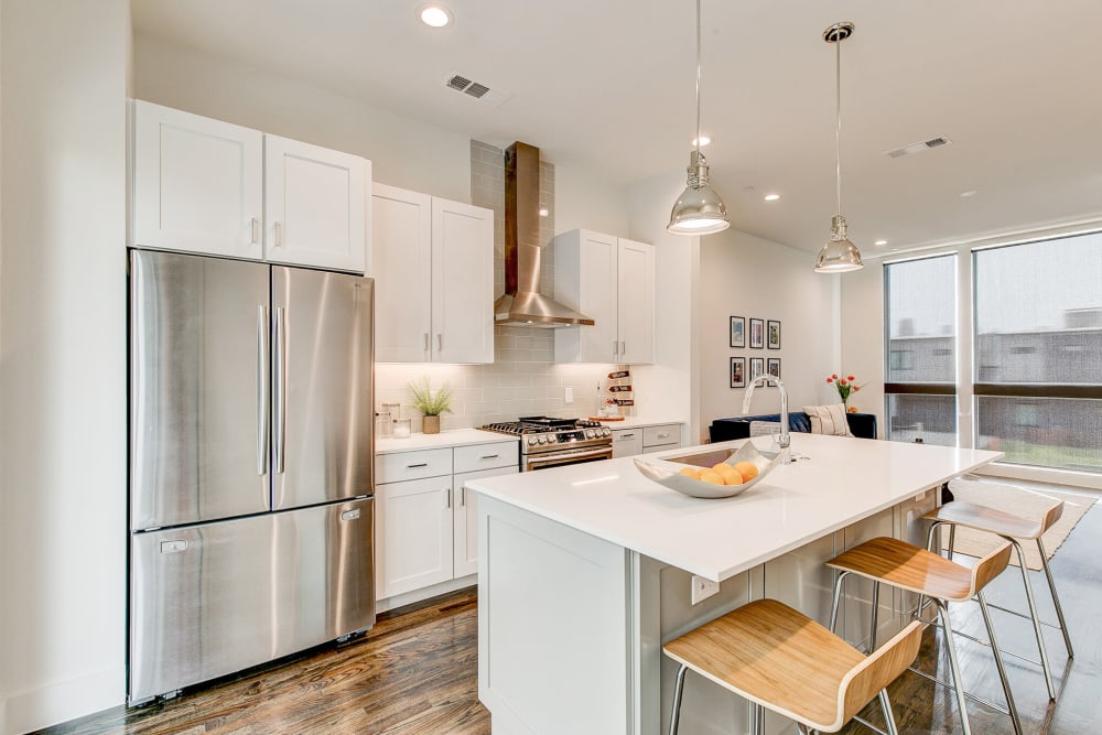 Large kitchen with stainless steel fridge and counter seating at The Collection Townhomes in Dallas, Texas